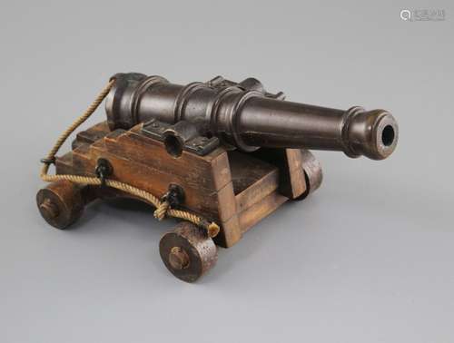 An early 20th century bronze model of a Naval cannon, on wooden trunnion base, length 25cm