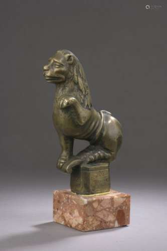 Bronze lion shown sitting down, left foreleg raise…