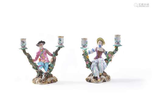 A pair of Meissen two-branch flower-encrusted figural candlesticks depicting gallant and companion