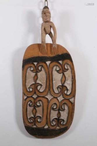 Papua, Asmat, ovale pigmentenschaalmet aan achterzijde gesneden motieven en bekroond met figuur., h.