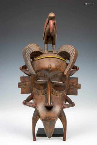 Senufo, face mask, kpelie, with two curved horns and surmounted by standing bird. With remnants of