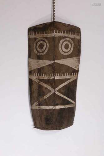 India, Naga, buffalo leather shieldwith painted stylized anthropomoroph face and rotan handle, l. 88