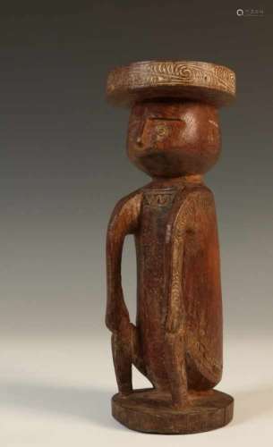 PNG, Massim, hard wooden figure, ca. 1940.A seated figure with fine carving on the disk shaped