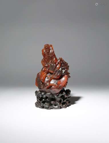 A CHINESE AMBER CARVING OF SHOULAO QING DYNASTY The God of Longevity depicted seated on rocks