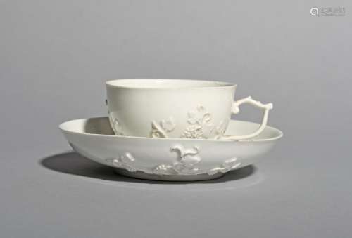 A Meissen teacup and saucer, c.1730, left in the white and applied with sprigs of fruiting