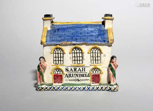 A large pearlware money box, 19th century, modelled as a house with arched doors and windows,