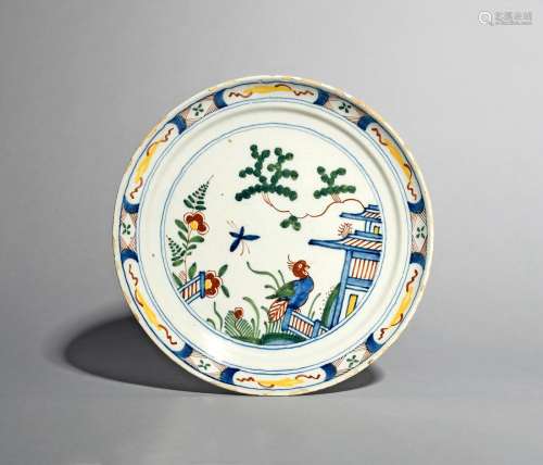 A delftware polychrome plate, c.1710, probably London, painted with a parrot perched on a low