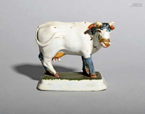 A Delft model of a cow, 18th century, standing four square on a shaped rectangular base with her