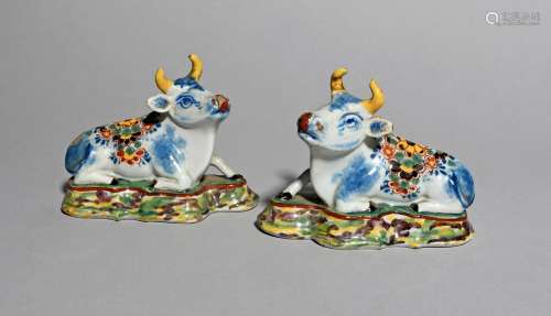 A small pair of Dutch Delft models of cows, 18th century, each recumbent on a shaped base marbled in