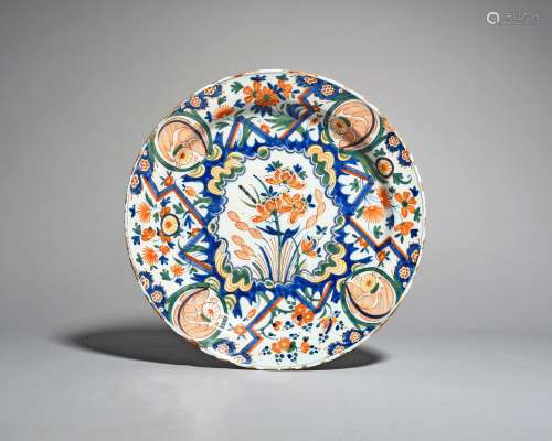 A Delft charger, c.1710-20, boldly painted in shades of red, blue, green and yellow with flowering