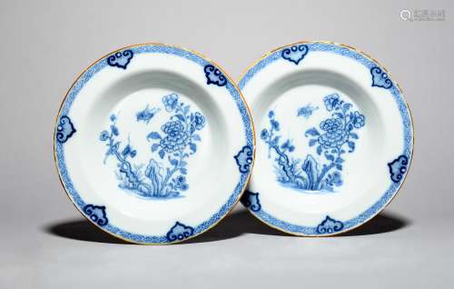 A pair of delftware soup plates, c.1760, each painted in blue with a bird in flight above peony
