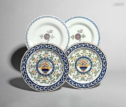Two pairs of Delft plates, 18th century, one pair painted with a central flower spray in blue, green