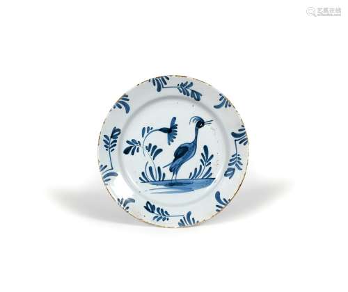 A delftware plate, c.1730, naively painted in blue with a large bird standing with beak agape beside