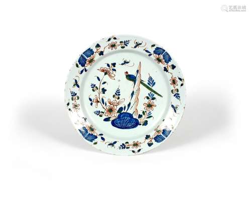 A delftware charger, c.1740, painted in red, blue and green with a long-tailed bird perched on