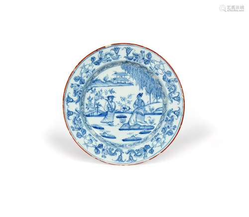 A delftware plate, c.1760, painted with two Chinese figures standing beneath a fringed tree in a