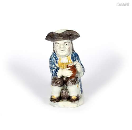 A Staffordshire pearlware Toby jug, c.1790, seated with an upright barrel between his feet, a