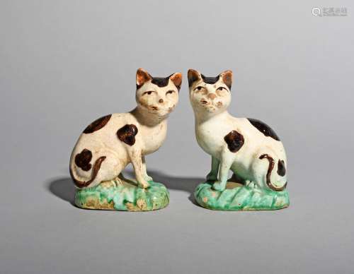 An unusual pair of faïence models of cats, probably 19th century, each seated on its haunches with
