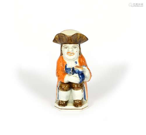 A Pratt ware Toby jug, c.1790-1800, resting a foaming jug of ale on his left knee, wearing a