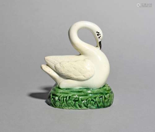 A Staffordshire model of a swan, c.1800, arching its long neck to touch its beak on its chest,