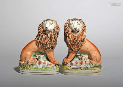 A pair of Staffordshire lion and lamb groups, 19th century, each lion seated on its haunches with