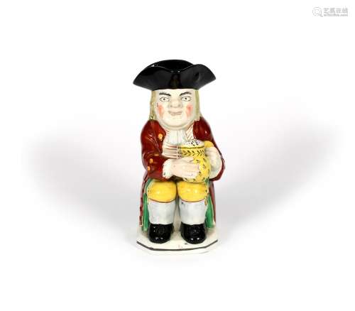 An Ordinary Toby jug, c.1810-20, seated and holding a foaming jug of ale decorated with black sprigs