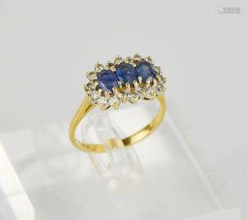 An 18ct gold, diamond and sapphire ring, set with three oval cut sapphires, bordered by diamonds,