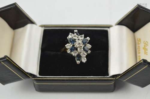 A gold (unmarked) dress ring, flower head form set with blue and white paste stones, size Q.
