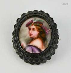 A 19th century porcelain portrait brooch, in a jet setting, depicting a lady wearing a hat, 3 by 2.