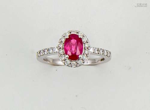 An 18ct white gold, ruby and diamond ring, the oval 1ct ruby surrounded by diamonds, and diamond set