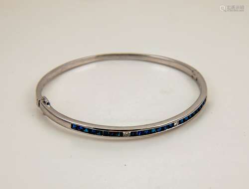 An 18ct white gold, sapphire and diamond set bangle, with 24 princess cut sapphires, and two