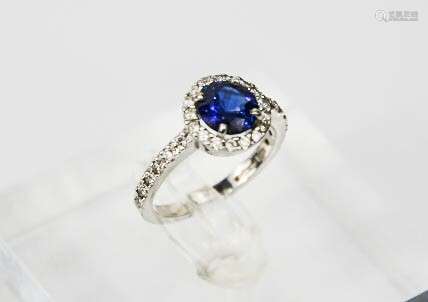 An 18ct white gold, sapphire and diamond ring, the brilliant cut 1.30ct sapphire, bordered by