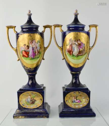 A pair of Victorian porcelain urns, with cobalt blue ground, depicting figural scenes, and having