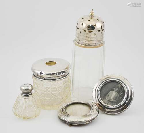 A silver and glass dressing table pot and jar, two silver picture frames, and a silver plated