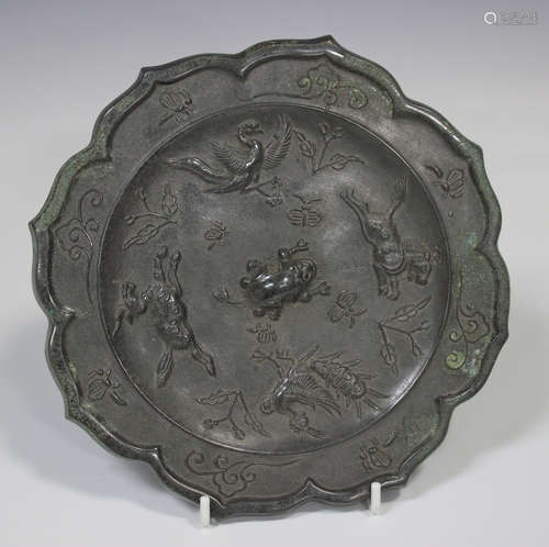 A Chinese silvered bronze mirror, of foliate outline, one side cast in relief with mythical beasts