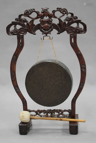 A Chinese hardwood gong stand and gong, early 20th century, the surmount carved and pierced in the