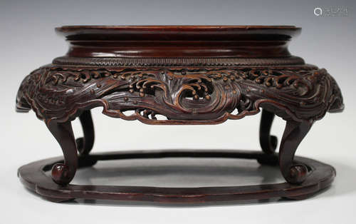 A Japanese carved hardwood stand, Meiji period, the oval top above a carved and pierced crashing