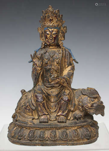 A Chinese gilt bronze figure group of Guanyin seated on the back of a recumbent Buddhistic lion,