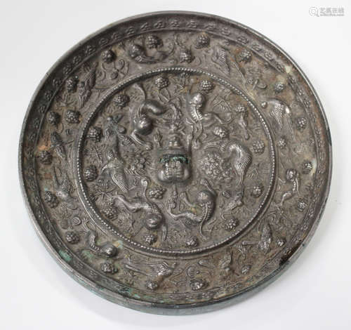 A Chinese Tang style silvered bronze circular mirror, cast in relief with the lion and grapevine