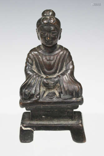 A South East Asian brown patinated bronze Buddha, modelled in a seated pose wearing a long robe,