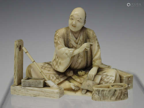 A Japanese carved ivory okimono figure of an artist, Meiji period, modelled seated wearing a long