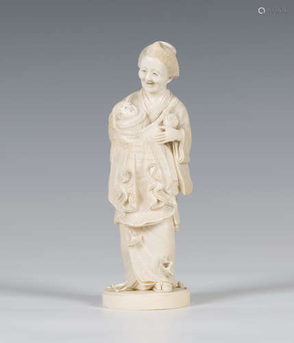 A Japanese carved ivory okimono figure, Meiji period, finely modelled as a lady carrying a baby,