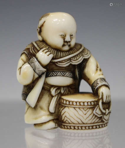 A Japanese carved and stained ivory netsuke, Meiji/Taisho period, finely carved as a boy carrying