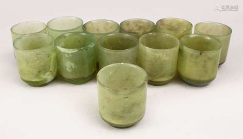 A GOOD SET OF TWELVE CHINESE CARVED GREEN JADE WINE CUPS, 6cm high x 5cm diameter.