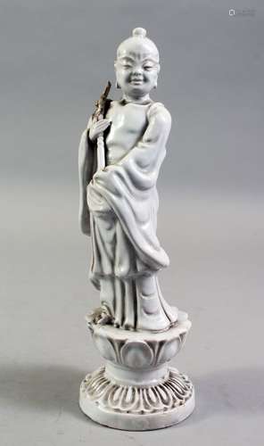 A CHINESE BLANC DE CHINE PORCELAIN FIGURE OF A BOY, standing holding a scepter, on a lotus base,