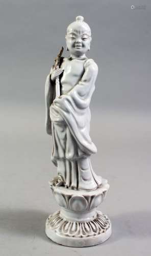 A CHINESE BLANC DE CHINE PORCELAIN FIGURE OF A BOY, standing holding a scepter, on a lotus base,