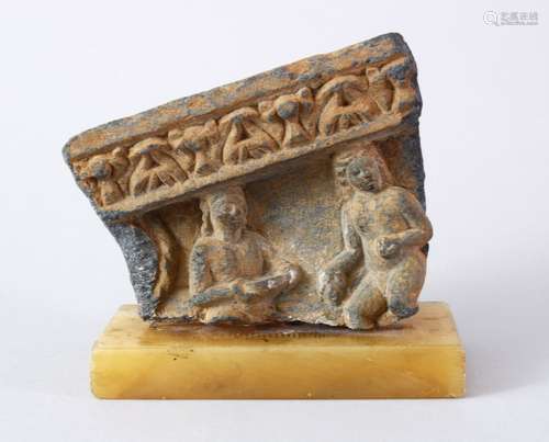 A GOOD 14TH CENTURY GHANDARA STONE FRAGMENT, of two figures beneath a border, mounted upon a stone