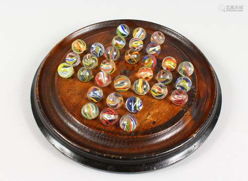 A WOODEN SOLITAIRE BOARD WITH AIR TWIST MARBLES. 10.5ins diameter.