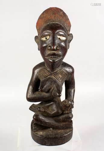 A GOOD TRIBAL CARVED WOOD SEATED MATERNAL FIGURE. 15ins high.