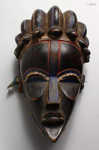 A GOOD CARVED WOOD TRIBAL MASK, with red and blue pigment. 11ins high.