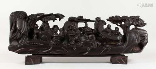 A LARGE CHINESE CARVED WOOD GROUP, many figures on a stand. 31ins long.